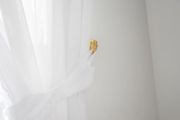 White curtain and hook gold color on the wall