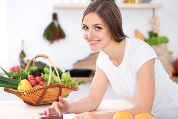 Young woman is making online shopping by tablet computer and credit card. Housewife found new recipe for  cooking in a kitchen