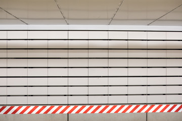 White subway tile and red and white striped caution sign or tape in a New York City subway station....