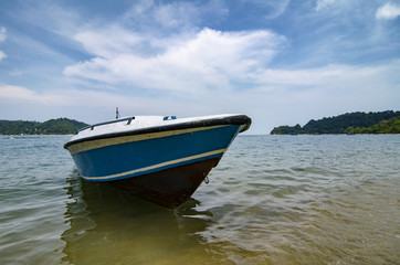 Pangkor Island located at Malaysia.Blue fiber boat moored over cloudy blue sky background