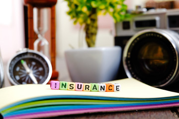 conceptual image with INSURANCE word block on note pad over soft focus bakground