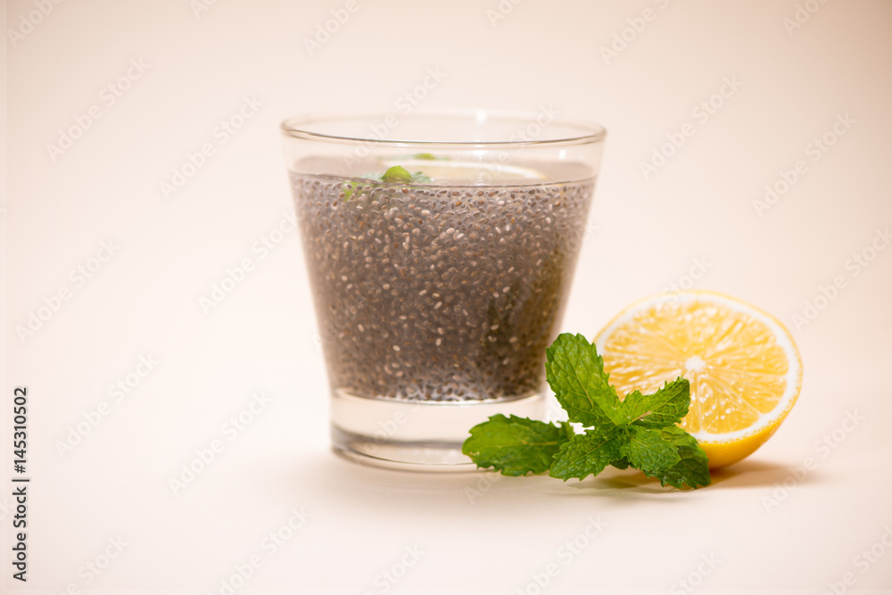 Wall mural selective focus of chia seeds drink with water in transparent glass with lemon balm.