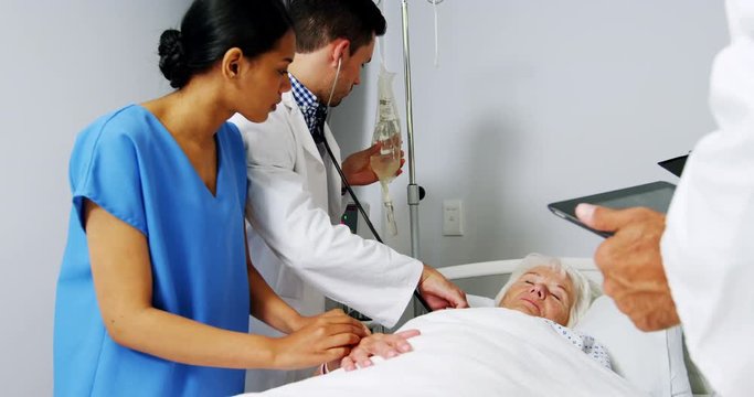 Doctors examining senior patient in ward 