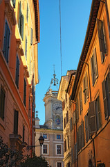 Fototapeta na wymiar The narrow street ended with a church. The tower is crowned with a dome of unusual shape. Rome. Italy