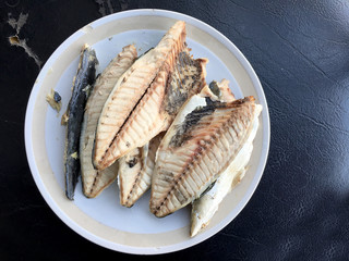 mackerel in white dish on black background.