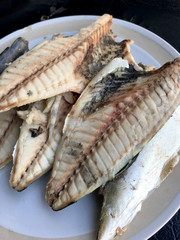 mackerel in white dish on black background.
