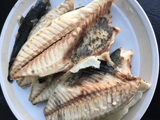mackerel in white dish on black background.