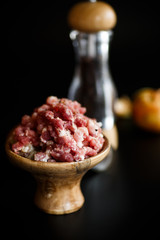 Chopped meat in a wooden bowl with spices