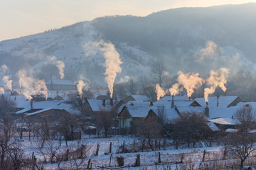 Beautiful winter scenery with smoke coming from house chimneys, on a bright, cold, morning, in...