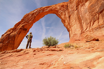 A hiker marvels at the Corona Arch in Utah.