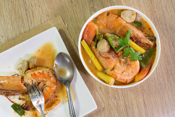Tom yum kung in white bowl and white dish on wooden table / Select focus.