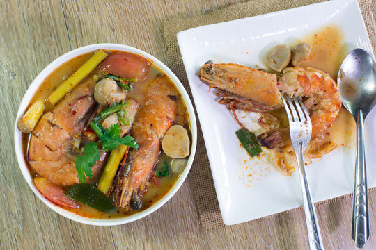 Tom yum kung in white bowl and white dish on wooden table / Select focus