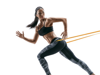 Strong woman using a resistance band in her exercise routine. Young woman performs fitness exercises on white background.