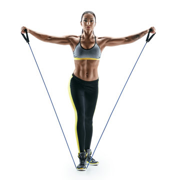 Attractive Muscular Woman Performs Exercises For Deltoid Muscles Using An Resistance Bands. Photo Of Young Brunette Isolated On White Background. Strength And Motivation