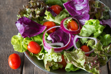 Close up of fresh vegetables salad in the bowl with rustic old wooden background. Healthy food concept.