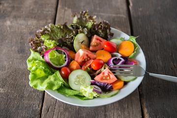 Close up of fresh vegetables salad in the bowl with rustic old wooden background. Healthy food concept.