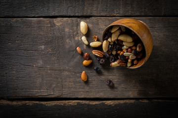 Close up of Mix nuts pouring from a bowl on wooden background.