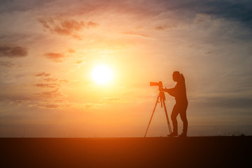 Silhouette of a photographer shoots a sunset.