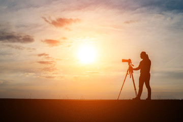 Silhouette of a photographer shoots a sunset.