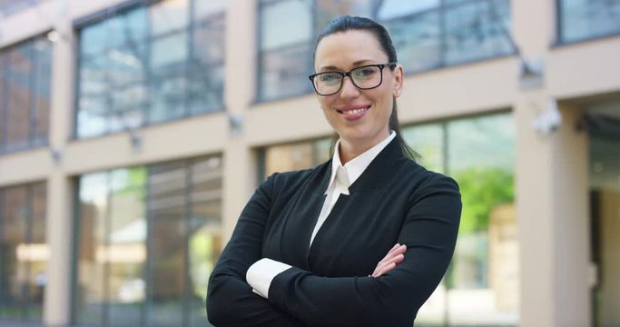 A woman in a suit, looks in camera and smiles proud and sure of himself, in the business centre. Concept of politics, business, finance, banking, insurance and testimonials for political campaign.