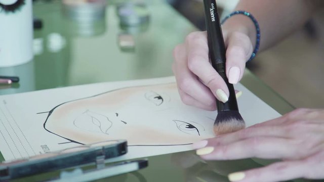 Close-up: color pallets with eye shadows, make-up brushes, lip glosses, colorful cosmetics on a glass table. Work desk stylist-make-up artist. The process of creating face chart