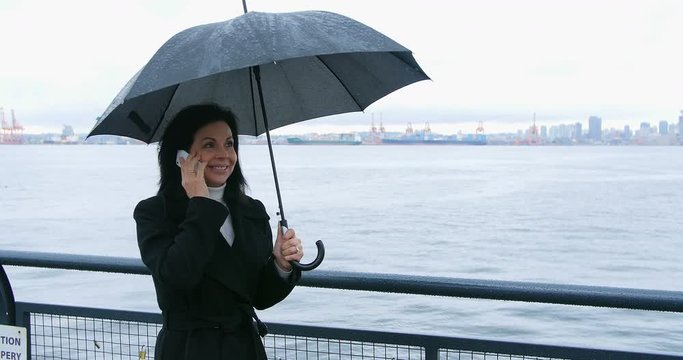 Woman holding umbrella and talking on mobile phone