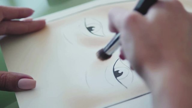 Inspiration: the make-up artist draws face-lines on watercolor paper, using professional cosmetics. Face sculpting - training on the face-chart. facechart makeup template for drawing cosmetics