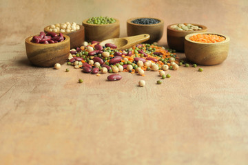 Various raw legumes in wooden bowls.