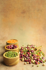 Various raw legumes in wooden bowls.