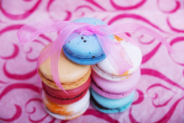 Tasty different colored macarons on pink background