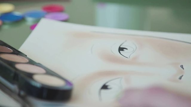 Inspiration: the make-up artist draws face-lines on watercolor paper, using professional cosmetics. Face sculpting - training on the face-chart. Make-up artist creates make-up sketch on the face chart