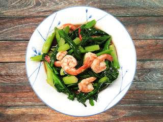 Thai food, Thai traditional food, fried young Chinese Kale With Prawn on wood table. Kale shrimp oyster.