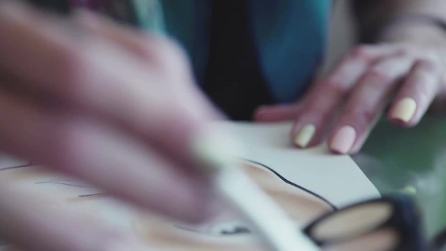 A woman make-up artist learns to apply make-up using the face map. Close-up: the make-up artist puts the skin tone on the face chart using a brush. Beauty and fashion industry: Facechart.