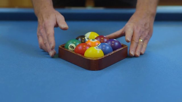 Man Racking Pool Balls in Nine-Ball Formation on Blue Billiards Table