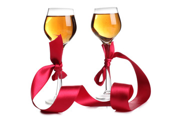 Wine glasses and a red ribbon on white background