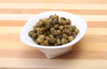 bowl with fresh capers on wooden table