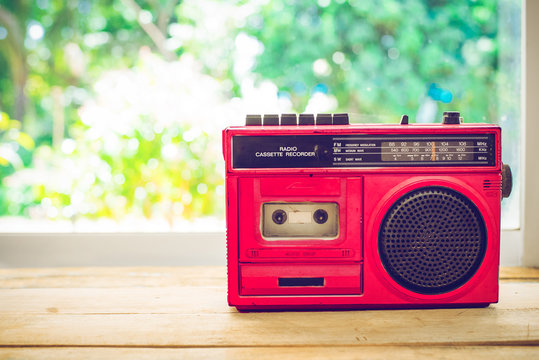Retro radio red color on table with nature background, vintage color filter