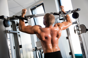 Muscular strong man working out at a gym.