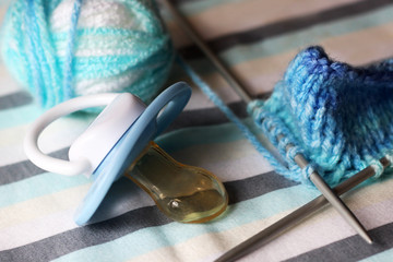 Children's pacifier and knitting needles.
