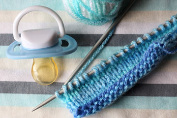 Children's pacifier and knitting needles.