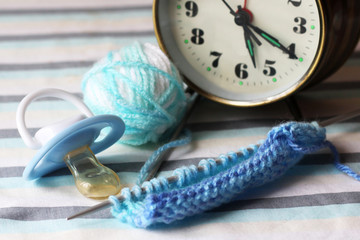 Children's pacifier and knitting needles.