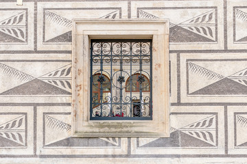 An ancient building visible through a barred window in the wall