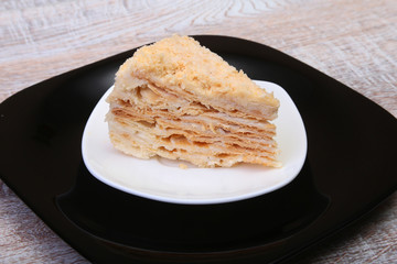 Homemade Napoleon puff cake on plate on wooden table close-up.