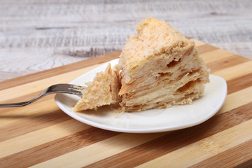 Homemade Napoleon puff cake on plate on wooden table close-up.