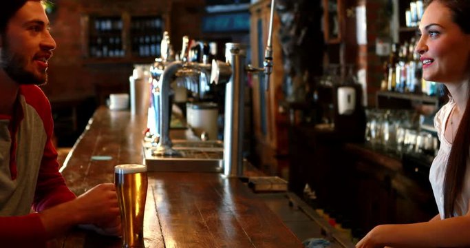 Barmaid interacting with male costumer while serving beer