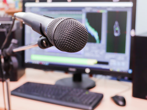 Microphone on the background of the computer monitor. Home recording Studio. Close-up. The focus in the foreground. Blurred background. Software for recording and editing sounds.
