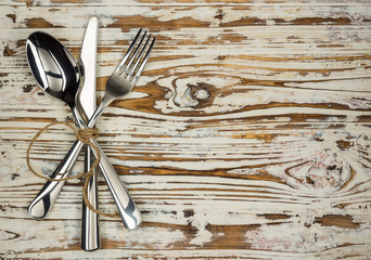 Crossed fork table knife and spoon on old wooden boards