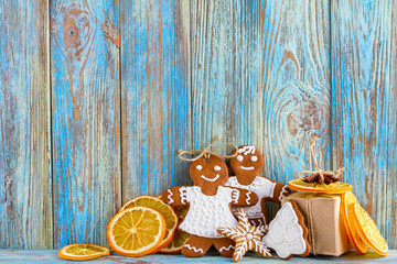 Still life of gingerbread, gingerbread men, dried oranges on blue wooden background, Christmas or New Year background, greeting card template