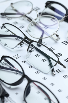 Glasses and eye chart on white background