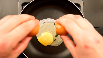 TOP VIEW: Human hands puts egg on the frying pan